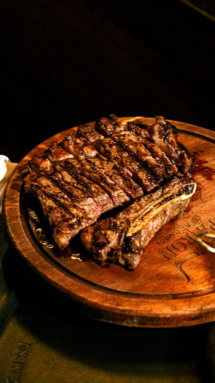 Juicy grilled ribeye steak sliced on a wooden serving board, perfect for a gourmet meal.
